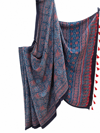 Indigo blue Ajrakh hand block print Modal silk saree featuring intricate paisley and floral motifs in rust red and dusty pink, with a decorative border and red tassels